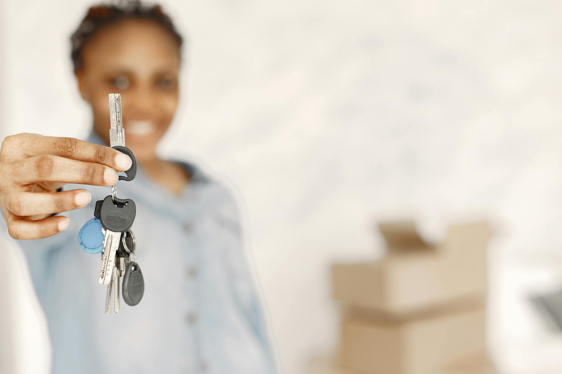 Woman holding house keys in a blurred background, representing new homeownership.
