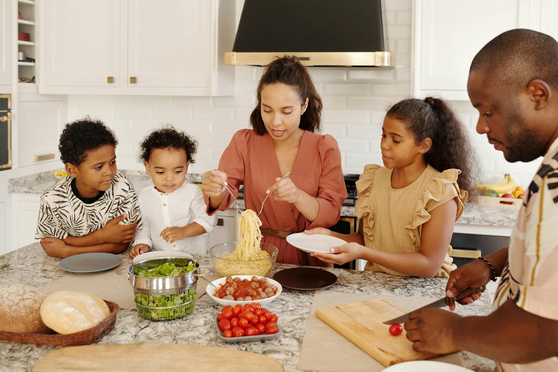 A family joyfully cooking together in a modern kitchen, preparing pasta and fresh vegetables.