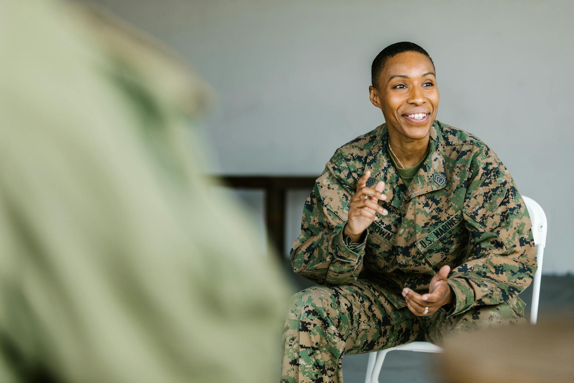 Joyful soldier in uniform engaging with others in a supportive indoor group session.