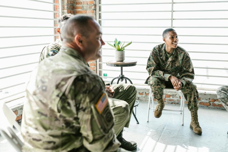 A group of military veterans sit in a circle, engaged in a supportive therapy session.