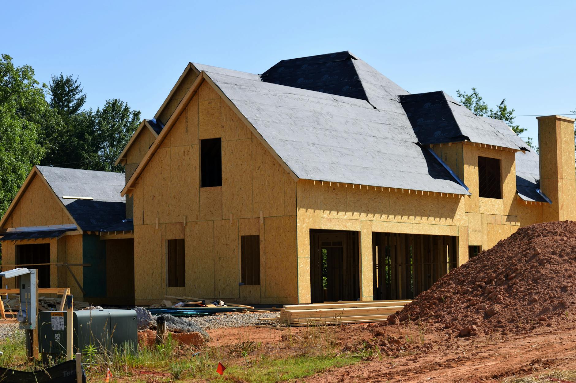 Partially built wooden house under construction, highlighting framing and design details in daylight.