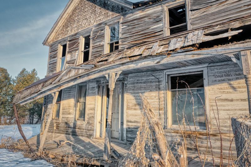 Dilapidated farmhouse in a snowy landscape, evoking a sense of nostalgic rural decay.