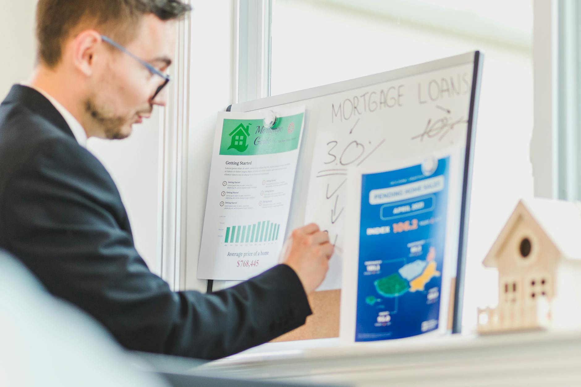 Real estate agent examining mortgage loan details on a whiteboard in a modern office setting.