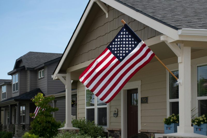 Vibrant American flag waving outside a stylish suburban house in bright daylight.