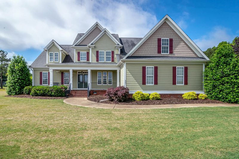 Beautiful two-story suburban house with a manicured lawn and inviting front porch.