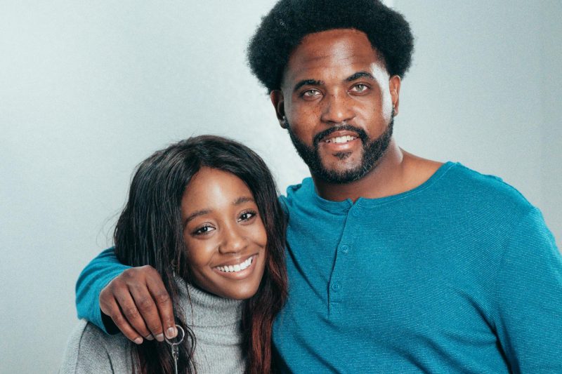 Smiling African American couple cheerfully holding house keys, celebrating their new home ownership.