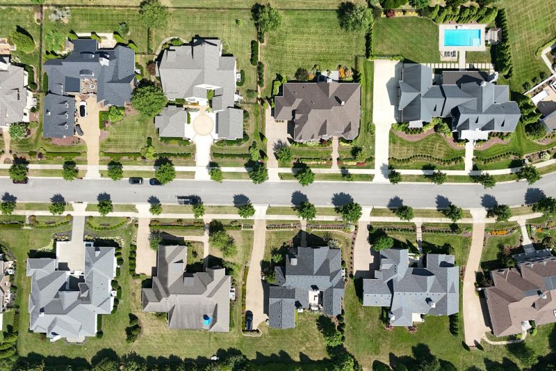 Overhead view of modern homes with lush greenery in a suburban neighborhood.
