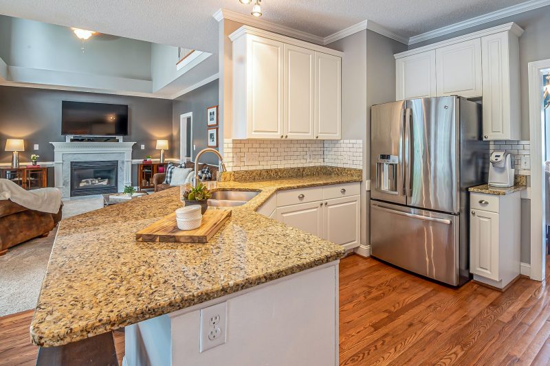 Luxurious open-concept kitchen with granite countertops and modern appliances, adjacent to a cozy living room featuring a fireplace.